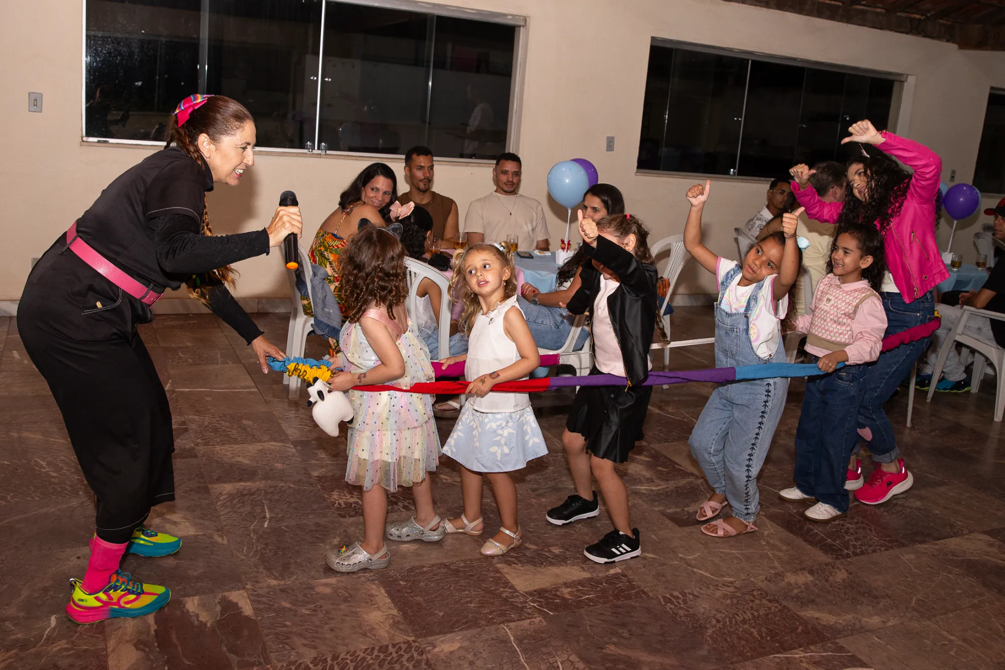 Recreadora conduzindo uma brincadeira com as crianças segurando uma faixa colorida