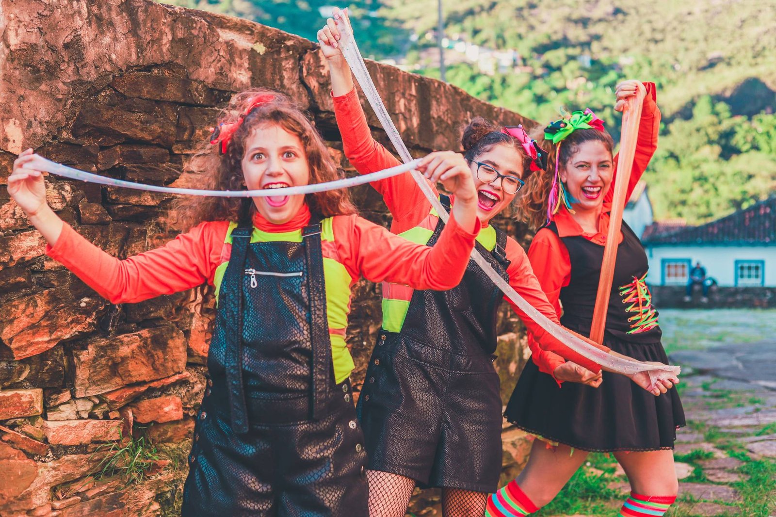 Recreadoras da Brincando de Brincar, fantasiadas e sorrindo, esticando geleca colorida